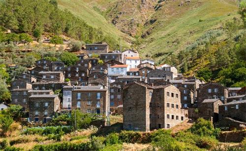alt="Traditional stone village houses built on a green mountain hillside in Portugal