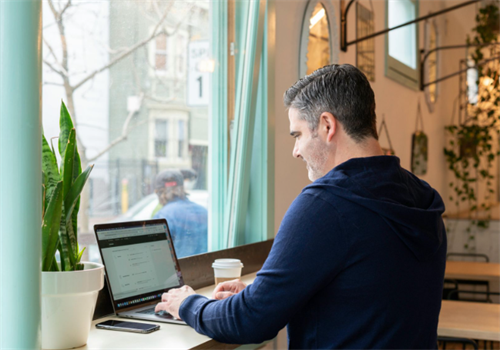 A man working on a laptop at a bright cafe workspace