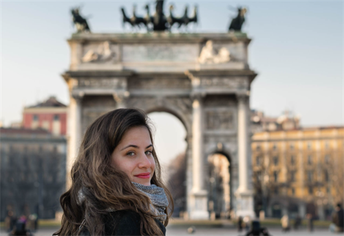 Young woman smiling in front of the Arco della Pace landmark in Milan