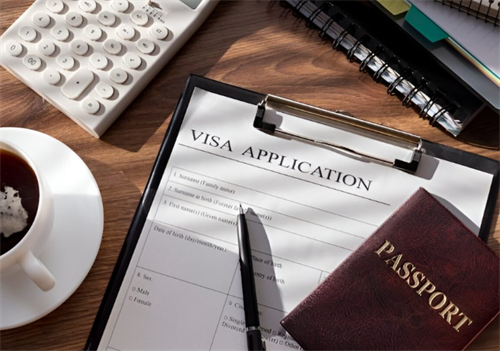 Visa application form with passport, pen, coffee cup and calculator on a wooden desk