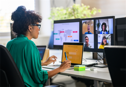 Woman in an office using multiple monitors for a video conference with remote team members