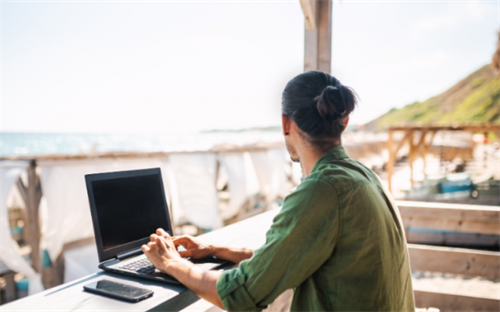 Man working remotely on a laptop at a coastal cafe in Portugal