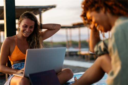 Woman working on a laptop at a beach bar in Croatia