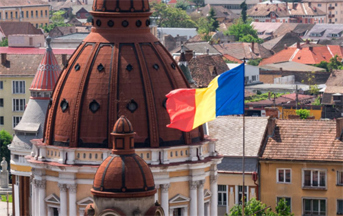 Romanian flag flying over historic city skyline