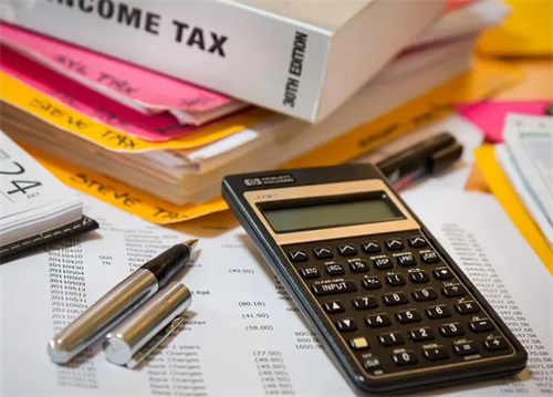 Tax documents, calculator and pen on desk with income tax book